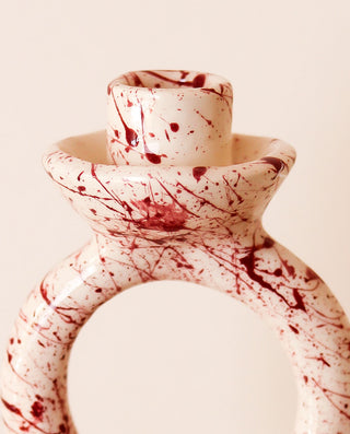 Ceramic candle holder with purple splatter design on a beige background