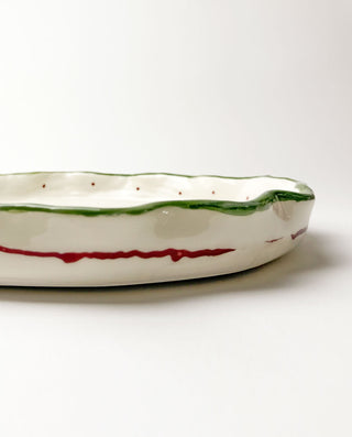Ceramic dish with green and red stripes on a white background