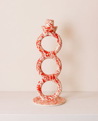 Decorative candle holder with red and white pattern on a light background