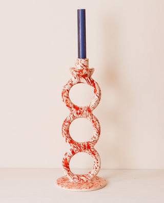 Decorative candle holder with red and white pattern on a plain background
