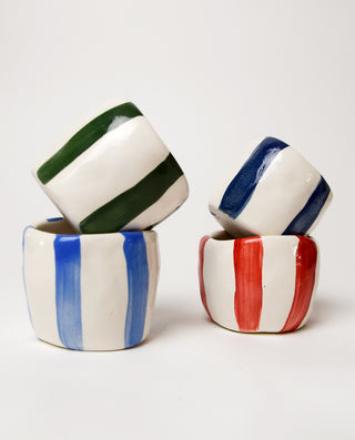 A set of four striped espresso cups, with stripes in different colors, arranged in a stacked fashion.