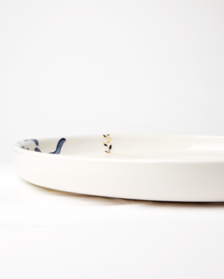 A ceramic serving platter with a royal blue floral pattern and gold accents on the edges.