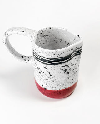 White Greek ceramic  pither with black speckles and red base on a white background