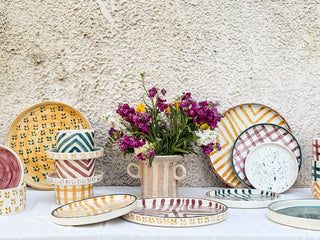 Colorful ceramic plates and bowls on a textured wall background
