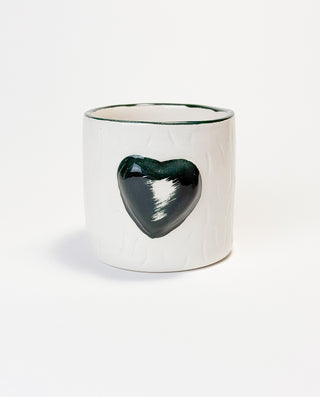 A white ceramic mug with a embossed green heart on the side.