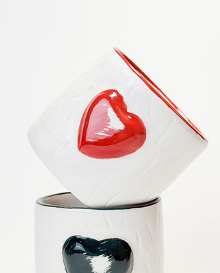 A white ceramic mug with a embossed red heart on the side