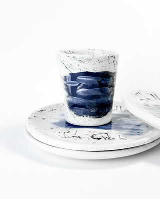 Ceramic cup with blue interior on a matching saucer against a white background