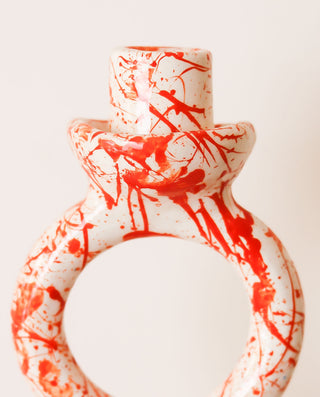 Decorative candle holder with red abstract patterns on a white background