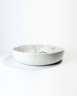 White ceramic bowl with speckled pattern on a white background