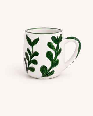 White mug with green leaf patterns on a white background