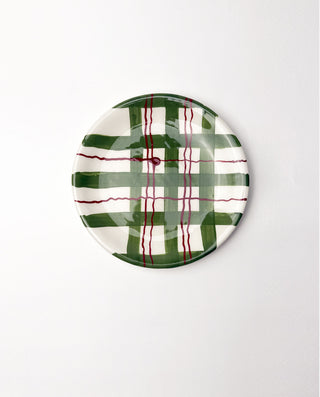 Round ceramic plate with green and red plaid pattern on a white background