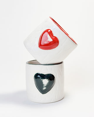 A white ceramic mug with a embossed green heart on the side.