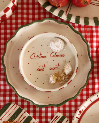 Decorative plate with 'Christmas Calories don't count' text on a red checkered tablecloth.