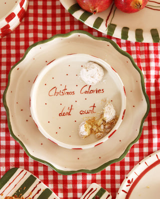 Decorative plate with 'Christmas Calories don't count' text on a red checkered tablecloth.