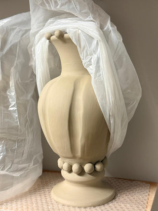 Beige decorative vase with a textured design on a neutral background