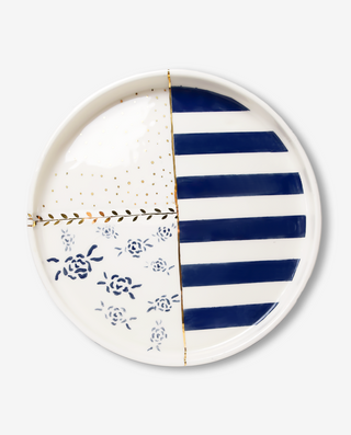 A ceramic serving platter with a royal blue and white color scheme, featuring gold details and a floral pattern on the white side, and a striped blue and white design on the other.