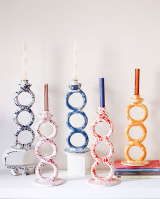 Set of five colorful candle holders on a white surface with a white background