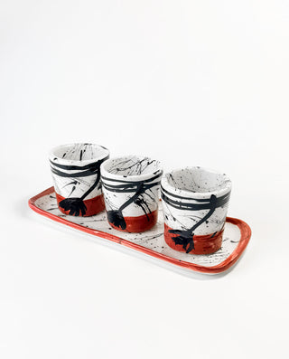 Three ceramic cups with black abstract designs on a white background