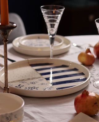 Dinner table setting with striped ceramic plates, glasses, and candles.