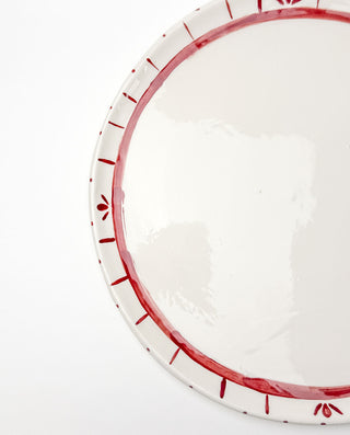 White festiveplate with red decorative rim on a white background