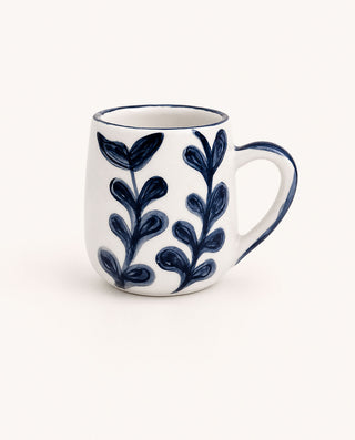White mug with blue leaf patterns on a white background