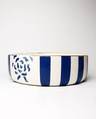 A ceramic salad bowl with horizontal royal blue stripes and a floral pattern around the rim.