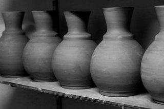 Row of ceramic vases on a shelf in a workshop setting