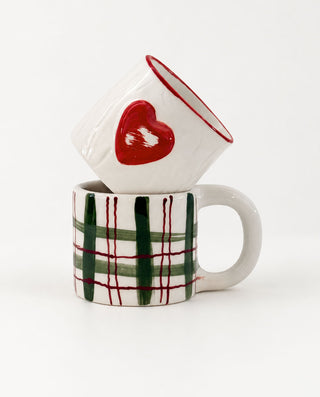 Handmade ceramic mug set featuring a red heart design paired with green and burgundy plaid.